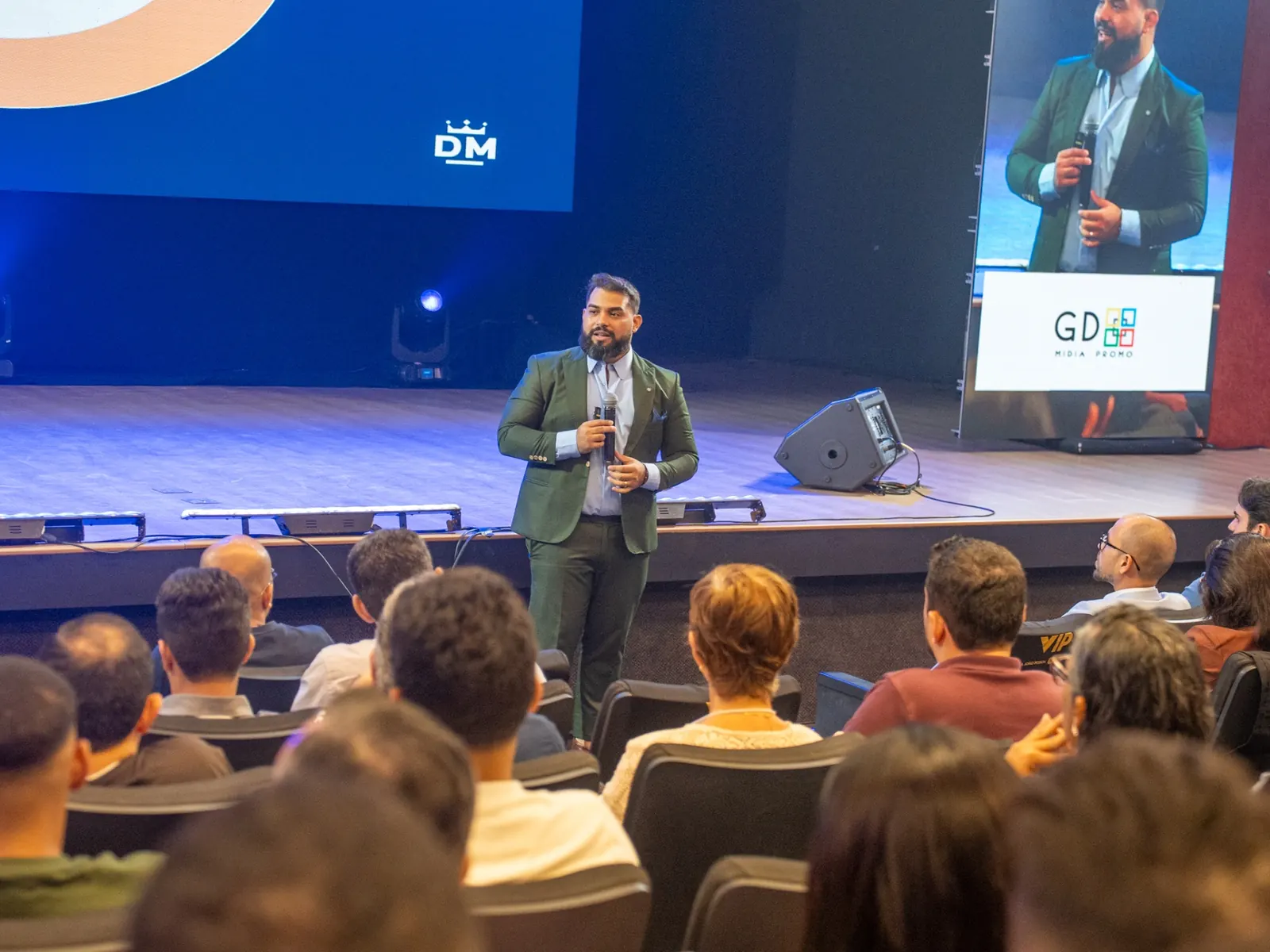 Daniel Morato palestrando no palco para plateia corporativa